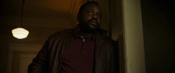 Movie still from “Child's Play” (2019), directed by Lars Klevberg – A man wearing a brown jacket standing next to a wall; Medium shot, Low angle