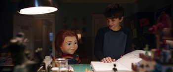 Movie still from “Child's Play” (2019), directed by Lars Klevberg – A boy and a girl sitting at a table with a doll; Medium shot, Over the shoulder angle