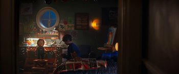 Movie still from “Child's Play” (2019), directed by Lars Klevberg – A boy sitting on a bed in a room with many paintings on the wall; Wide shot, Over the shoulder angle