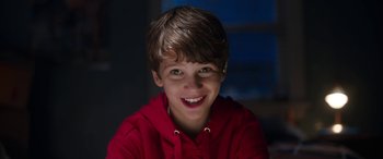 Movie still from “Child's Play” (2019), directed by Lars Klevberg – A young boy wearing a red hoodie smiling for the camera; Close Up shot, High angle