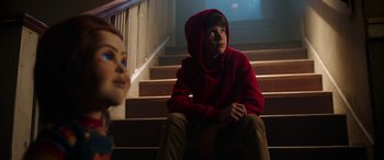 Movie still from “Child's Play” (2019), directed by Lars Klevberg – A young boy sitting on the steps of a staircase; Medium shot, Over the shoulder angle