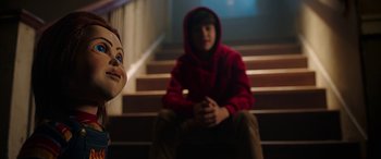 Movie still from “Child's Play” (2019), directed by Lars Klevberg – A person sitting on a set of stairs with a mask on; Close Up shot, Over the shoulder angle