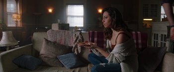 Movie still from “Child's Play” (2019), directed by Lars Klevberg – A woman sitting on a couch holding a piece of pizza; Medium shot, Over the shoulder angle
