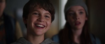 Movie still from “Child's Play” (2019), directed by Lars Klevberg – A young boy smiling at the camera while a woman looks on; Close Up shot, Over the shoulder angle