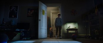 Movie still from “Child's Play” (2019), directed by Lars Klevberg – A boy and a doll standing in front of an open door; Wide shot, Over the shoulder angle