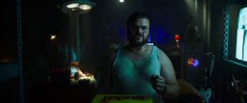 Movie still from “Child's Play” (2019), directed by Lars Klevberg – A man in a white tank top holding a box; Medium shot, Low angle