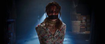 Movie still from “Child's Play” (2019), directed by Lars Klevberg – A woman in a floral shirt with a mouth taped to her face; Medium shot, Over the shoulder angle