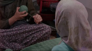 Movie still from “Children of Heaven” (1997), directed by Majid Majidi – Two people sitting on the floor knitting a green ball of yarn; Close Up shot, High angle
