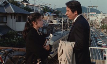 Movie still from “Chizuko's Younger Sister” (1991), directed by Nobuhiko Ôbayashi – A man and a woman are standing next to each other; Medium shot, Over the shoulder angle