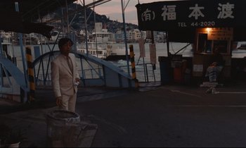 Movie still from “Chizuko's Younger Sister” (1991), directed by Nobuhiko Ôbayashi – A man standing on a dock near a body of water; Wide shot, High angle