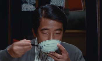 Movie still from “Chizuko's Younger Sister” (1991), directed by Nobuhiko Ôbayashi – A man holding a bowl up to his face; Close Up shot, High angle