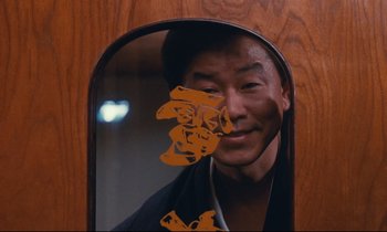 Movie still from “Chizuko's Younger Sister” (1991), directed by Nobuhiko Ôbayashi – A man is reflected in a mirror with chinese writing on it; Close Up shot, Low angle