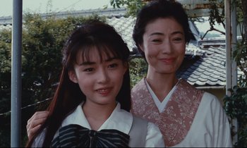 Movie still from “Chizuko's Younger Sister” (1991), directed by Nobuhiko Ôbayashi – Two young women standing next to each other in front of a building; Close Up shot, Low angle