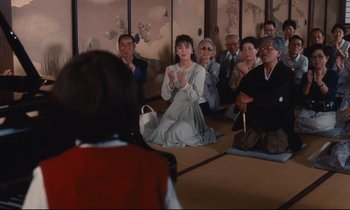 Movie still from “Chizuko's Younger Sister” (1991), directed by Nobuhiko Ôbayashi – A group of people sitting in front of a wall; Medium shot, Over the shoulder angle