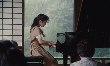 Movie still from “Chizuko's Younger Sister” (1991), directed by Nobuhiko Ôbayashi – A girl in a dress playing the piano; Medium shot, High angle