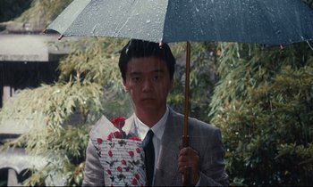 Movie still from “Chizuko's Younger Sister” (1991), directed by Nobuhiko Ôbayashi – A man holding an umbrella with flowers in it; Medium shot, High angle