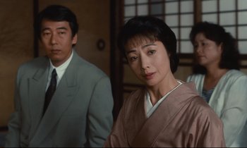 Movie still from “Chizuko's Younger Sister” (1991), directed by Nobuhiko Ôbayashi – A man and a woman standing next to each other in front of another man; Close Up shot, Low angle