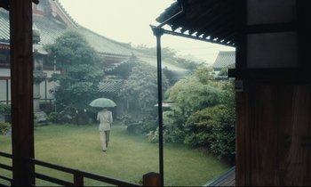 Movie still from “Chizuko's Younger Sister” (1991), directed by Nobuhiko Ôbayashi – A man holding an umbrella in the rain; Extreme Wide shot, Low angle
