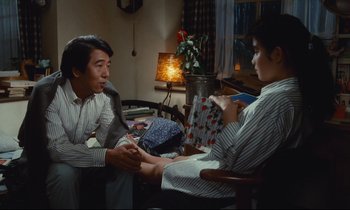 Movie still from “Chizuko's Younger Sister” (1991), directed by Nobuhiko Ôbayashi – A man and a woman sitting on a chair in a room; Medium shot, High angle