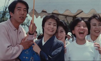 Movie still from “Chizuko's Younger Sister” (1991), directed by Nobuhiko Ôbayashi – A group of people standing under an umbrella; Medium shot, Low angle
