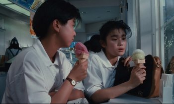 Movie still from “Chizuko's Younger Sister” (1991), directed by Nobuhiko Ôbayashi – Two people sitting at a table eating ice cream; Medium shot, Over the shoulder angle
