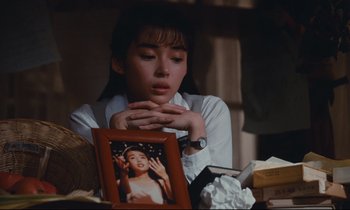 Movie still from “Chizuko's Younger Sister” (1991), directed by Nobuhiko Ôbayashi – A woman sitting in front of a framed picture; Close Up shot, Over the shoulder angle