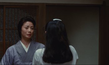 Movie still from “Chizuko's Younger Sister” (1991), directed by Nobuhiko Ôbayashi – A woman standing in front of a mirror looking in the mirror; Medium shot, Over the shoulder angle