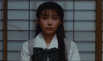 Movie still from “Chizuko's Younger Sister” (1991), directed by Nobuhiko Ôbayashi – A woman with long black hair wearing a white shirt and a black bow tie; Close Up shot, Low angle
