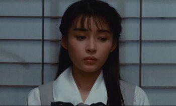 Movie still from “Chizuko's Younger Sister” (1991), directed by Nobuhiko Ôbayashi – A woman with long black hair wearing a white shirt and a black bow tie; Close Up shot, Low angle