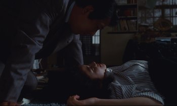 Movie still from “Chizuko's Younger Sister” (1991), directed by Nobuhiko Ôbayashi – A man and a woman laying on a bed in a living room; Medium shot, High angle