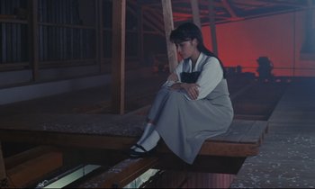 Movie still from “Chizuko's Younger Sister” (1991), directed by Nobuhiko Ôbayashi – A woman sitting on the edge of a bridge; Wide shot, Low angle