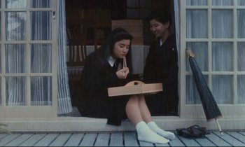 Movie still from “Chizuko's Younger Sister” (1991), directed by Nobuhiko Ôbayashi – Two women sitting on a porch eating pizza; Medium shot, High angle