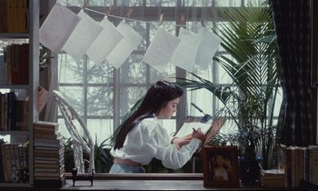 Movie still from “Chizuko's Younger Sister” (1991), directed by Nobuhiko Ôbayashi – A woman sitting on a chair in front of a window; Wide shot, Low angle