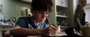 Movie still from “The Dark Tower” (2017), directed by Nikolaj Arcel – A young boy is writing on a piece of paper; Close Up shot, Low angle