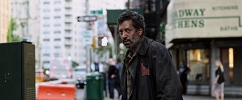 Movie still from “The Dark Tower” (2017), directed by Nikolaj Arcel – A man in a brown jacket is walking down the street; Medium shot, Low angle