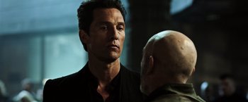 Movie still from “The Dark Tower” (2017), directed by Nikolaj Arcel – A man standing next to another man in front of a building; Close Up shot, Over the shoulder angle