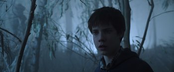Movie still from “The Dark Tower” (2017), directed by Nikolaj Arcel – A young man is standing in front of a tree; Close Up shot, Low angle