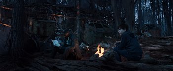 Movie still from “The Dark Tower” (2017), directed by Nikolaj Arcel – Two people sitting around a fire in the woods; Wide shot, High angle