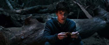 Movie still from “The Dark Tower” (2017), directed by Nikolaj Arcel – A man sitting on the ground holding a piece of food; Close Up shot, High angle