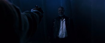 Movie still from “The Dark Tower” (2017), directed by Nikolaj Arcel – A man in a dark room with a gun pointed at him; Medium shot, Over the shoulder angle