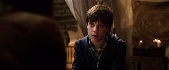 Movie still from “The Dark Tower” (2017), directed by Nikolaj Arcel – A young man sitting in front of a curtain; Close Up shot, Over the shoulder angle