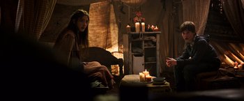 Movie still from “The Dark Tower” (2017), directed by Nikolaj Arcel – A woman sitting on a chair next to candles; Medium shot, Over the shoulder angle