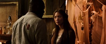 Movie still from “The Dark Tower” (2017), directed by Nikolaj Arcel – A woman standing next to a man in front of a wooden wall; Close Up shot, Over the shoulder angle