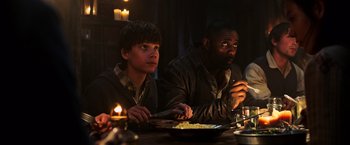 Movie still from “The Dark Tower” (2017), directed by Nikolaj Arcel – Two people sitting at a table eating food; Medium shot, High angle