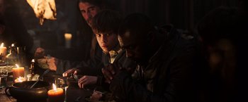 Movie still from “The Dark Tower” (2017), directed by Nikolaj Arcel – A group of people sitting at a table with food on it; Medium shot, Over the shoulder angle