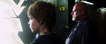 Movie still from “The Dark Tower” (2017), directed by Nikolaj Arcel – A man standing next to a boy in a room; Close Up shot, Low angle