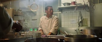 Movie still from “The Dark Tower” (2017), directed by Nikolaj Arcel – A man wearing a white chef's outfit in a kitchen; Medium shot, Low angle