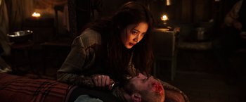 Movie still from “The Dark Tower” (2017), directed by Nikolaj Arcel – A woman is cutting a man's head with a knife; Medium shot, Over the shoulder angle