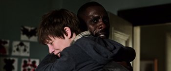Movie still from “The Dark Tower” (2017), directed by Nikolaj Arcel – Two men are hugging in a dark room; Close Up shot, Over the shoulder angle