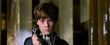 Movie still from “The Dark Tower” (2017), directed by Nikolaj Arcel – A young man holding a gun in his hand; Close Up shot, Over the shoulder angle